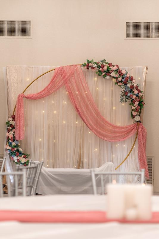 Floral arch backdrop with pink draping